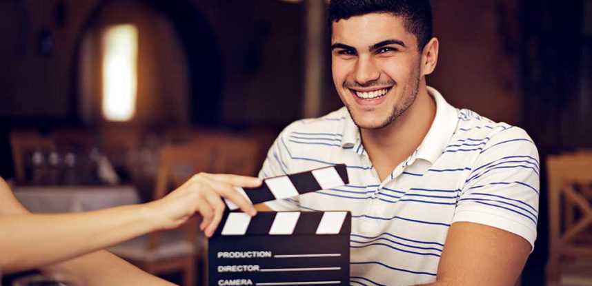 An actor performing on stage, holding a script in one hand and gesturing with the other.